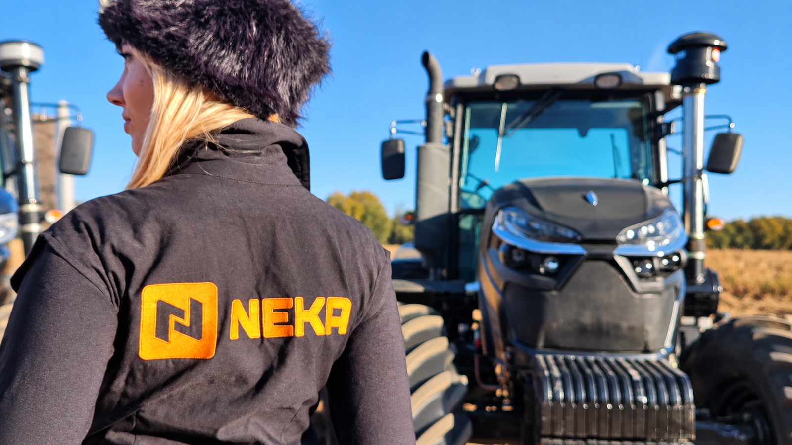 Kiara con indumentaria NEKA frente a un tractor de la marca